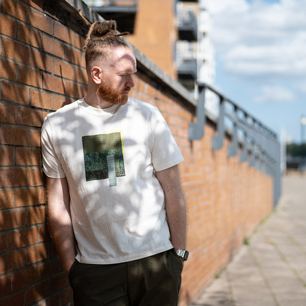 Newton Faulkner leaning on a brick wall in the shade
