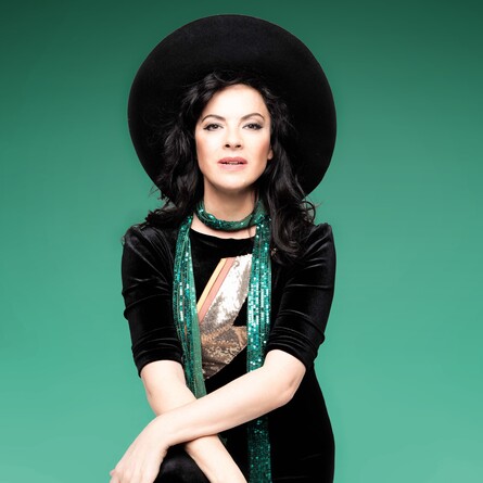 Camille wearing a big black hat on a green background